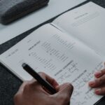 a person writing on a notebook with a pen